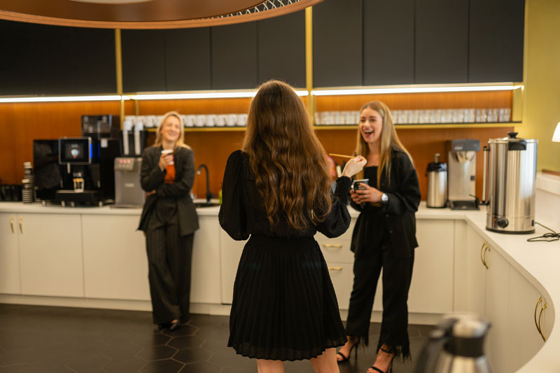 Tre glada personer som tar en kaffepaus i köket på ett kontor